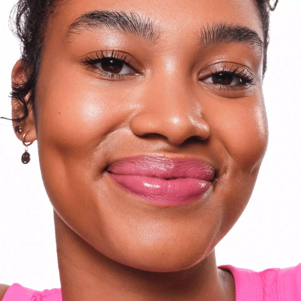 Portrait d'une femme avec un LIP TINT rose. Elle sourit.