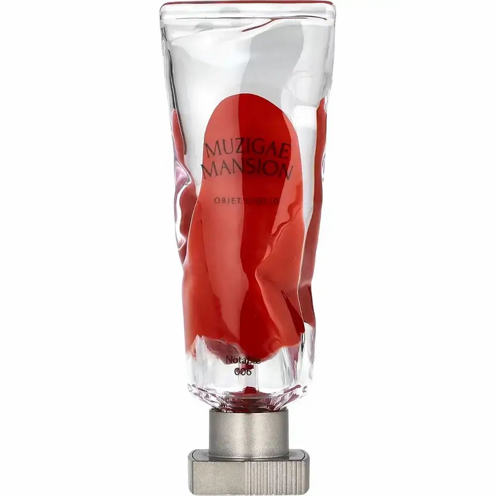 Objet liptint in tube. Transparante behuizing, rode inhoud. Merk: MUZIGAE MANSION. Productnaam en kleurnummer zichtbaar.