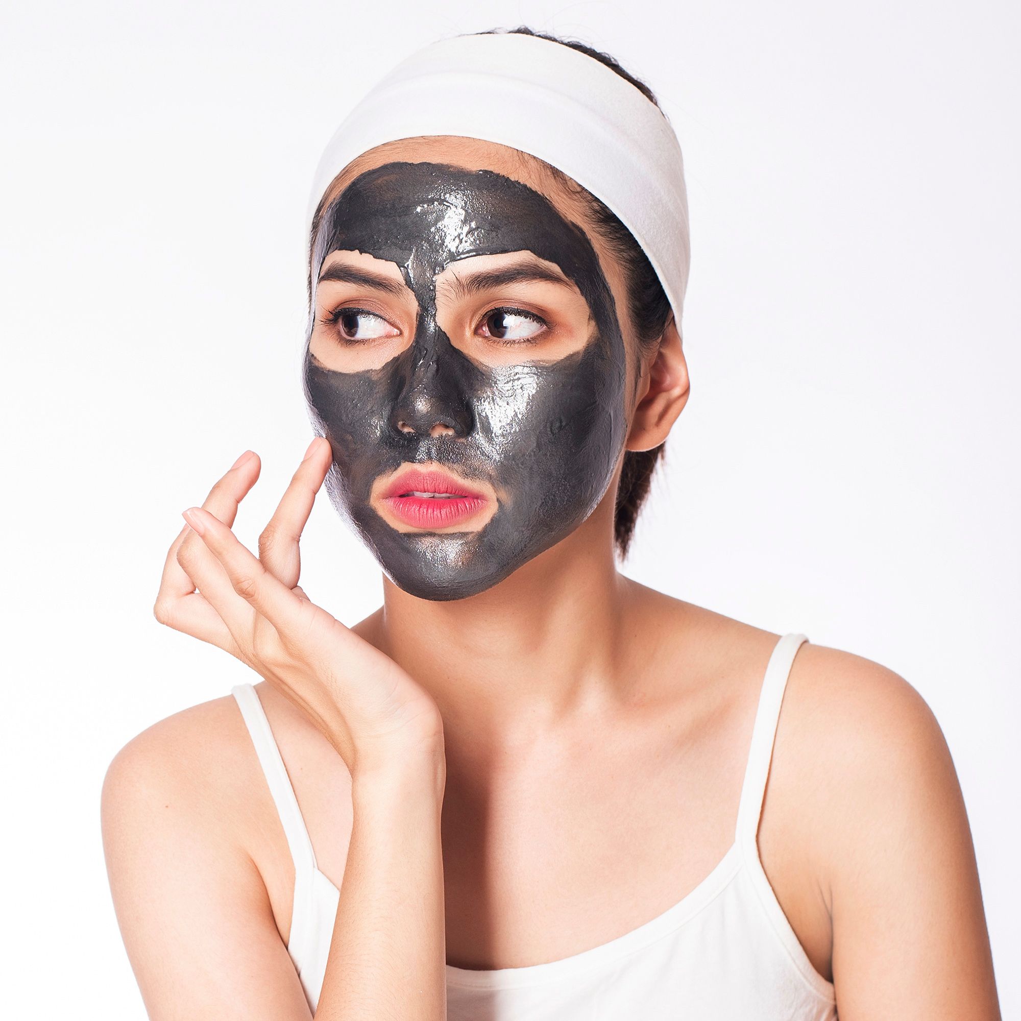 Vrouw met gezichtsmasker en haarband. Gezicht bedekt met masker, raakt de huid aan.