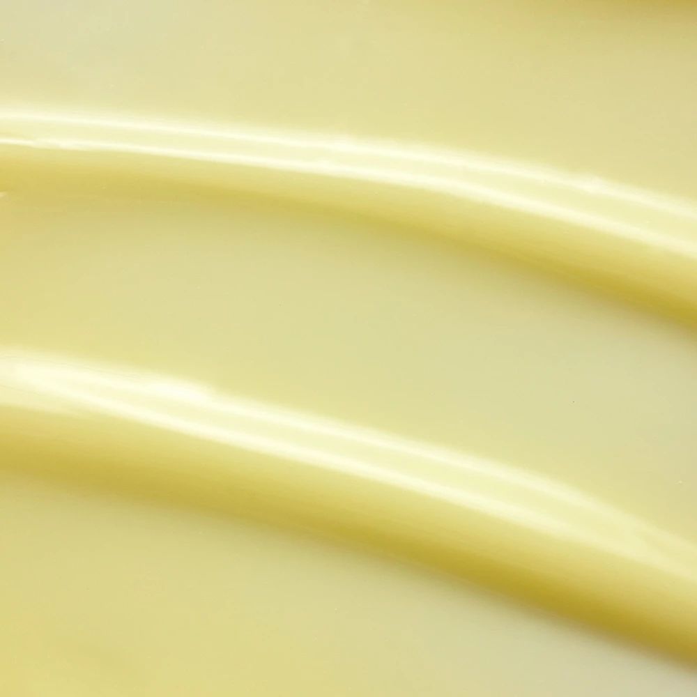 Gros plan de crème jaune. Deux bandes ondulées. Aucune inscription visible.