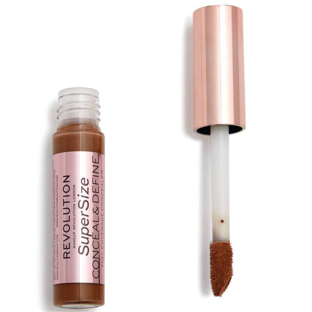 Flacon de correcteur avec applicateur. Bouchon or rose. Nom du produit et marque visibles.