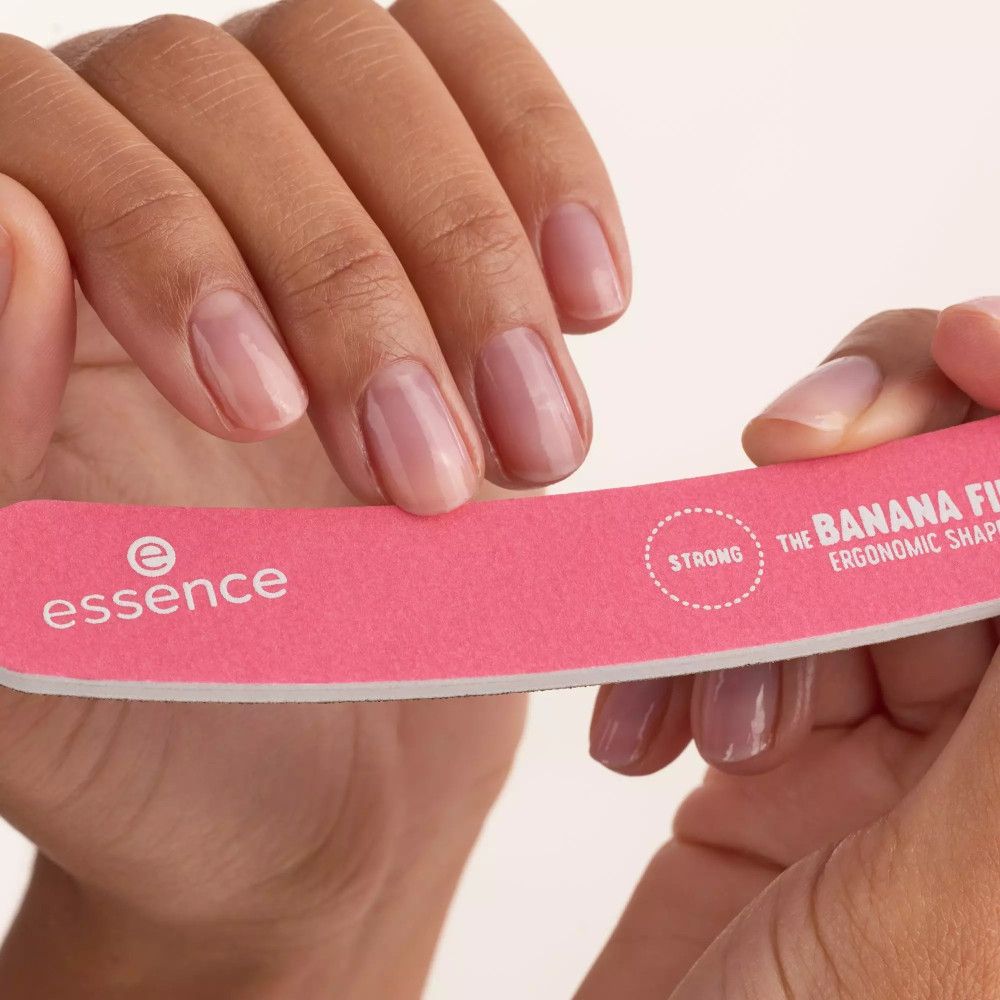 Handen houden een roze nagelvijl vast. Opschrift: "THE BANANA FILE", "STRONG". Merk: Essence.