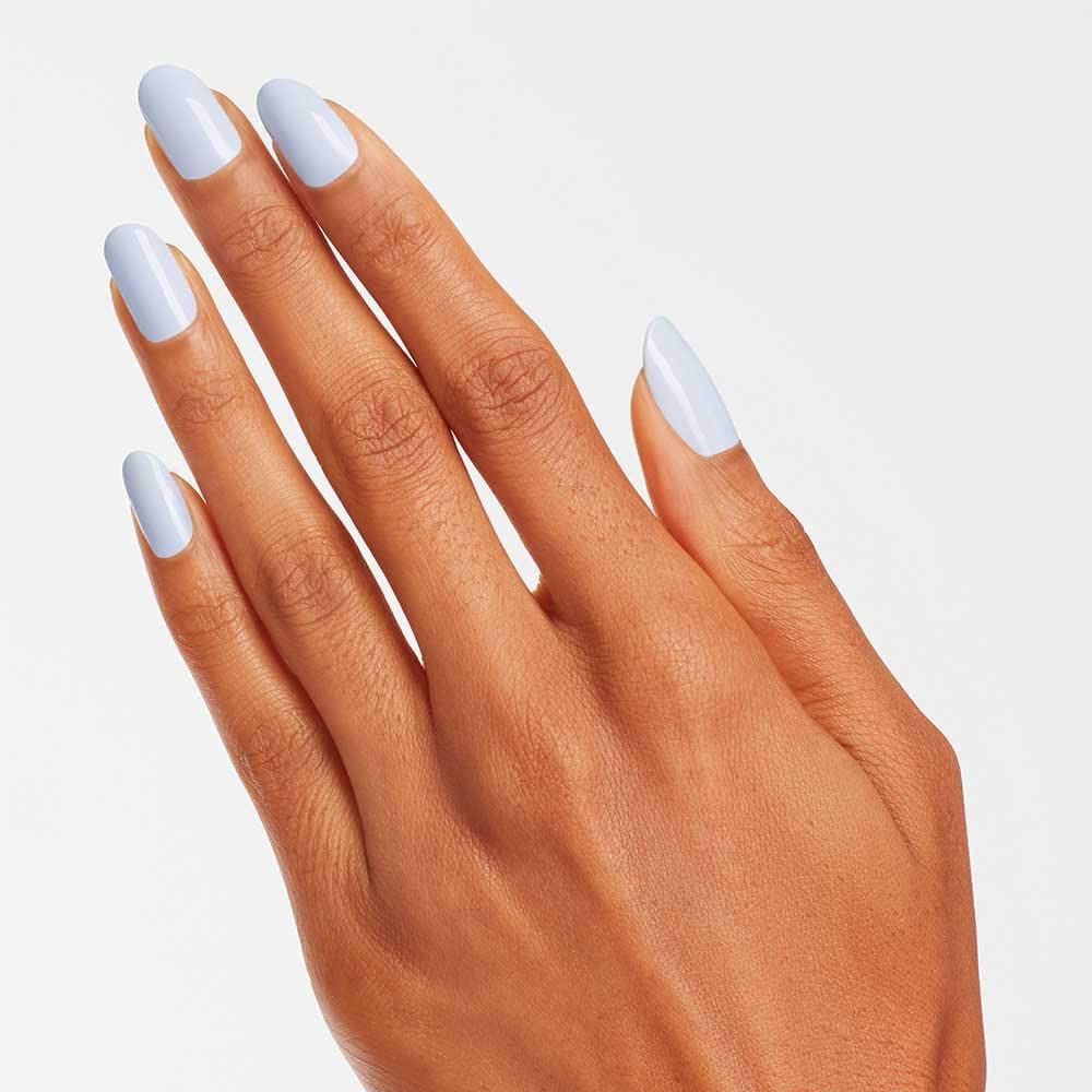 Main avec ongles peints en bleu clair. Les ongles sont de forme ovale et brillants.