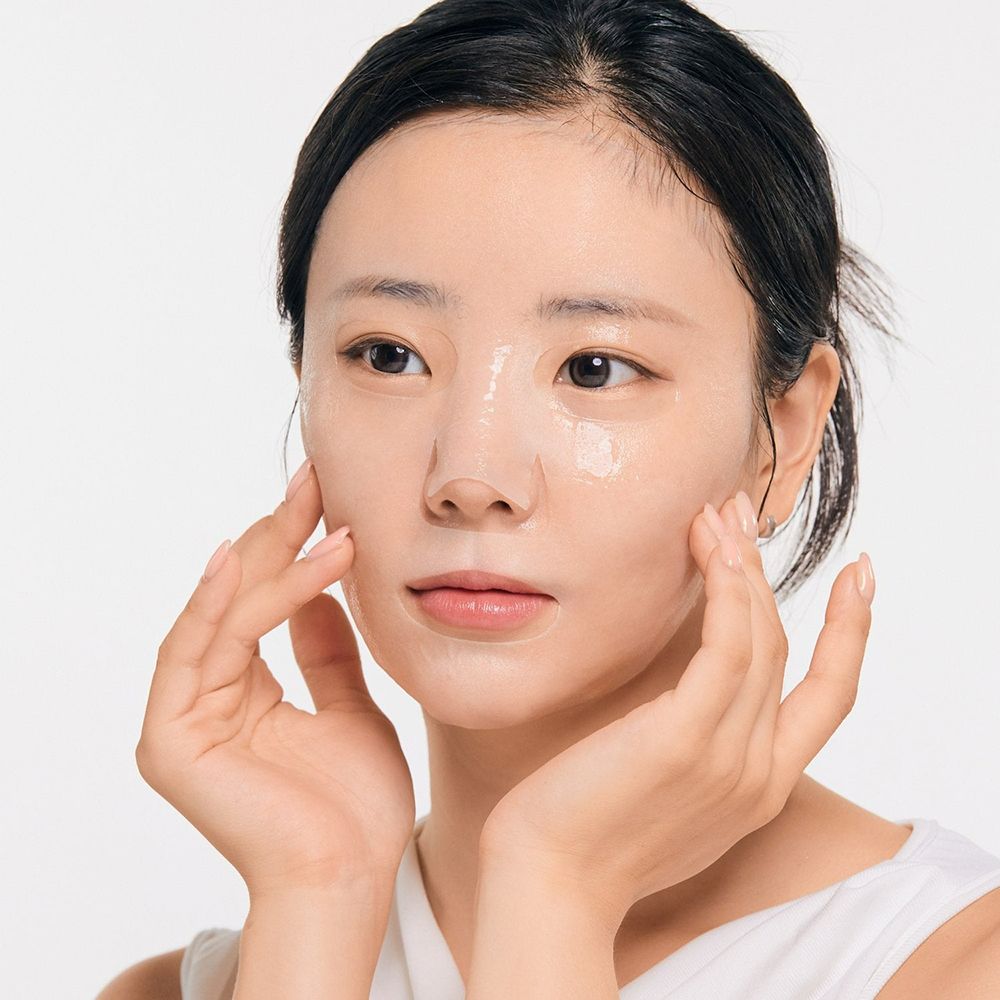 Persoon met gezichtsmasker op het gezicht. Handen raken het gezicht aan. Achtergrond: wit.