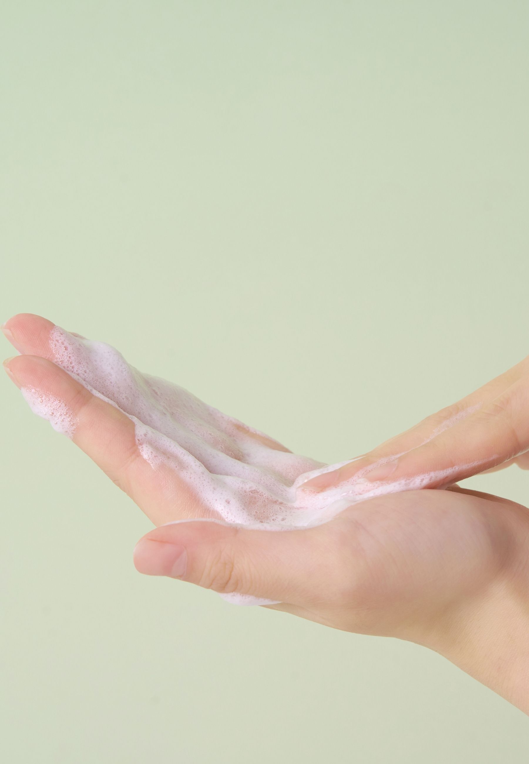 Handen bedekt met schuim. Schuimige textuur. Groene achtergrond.