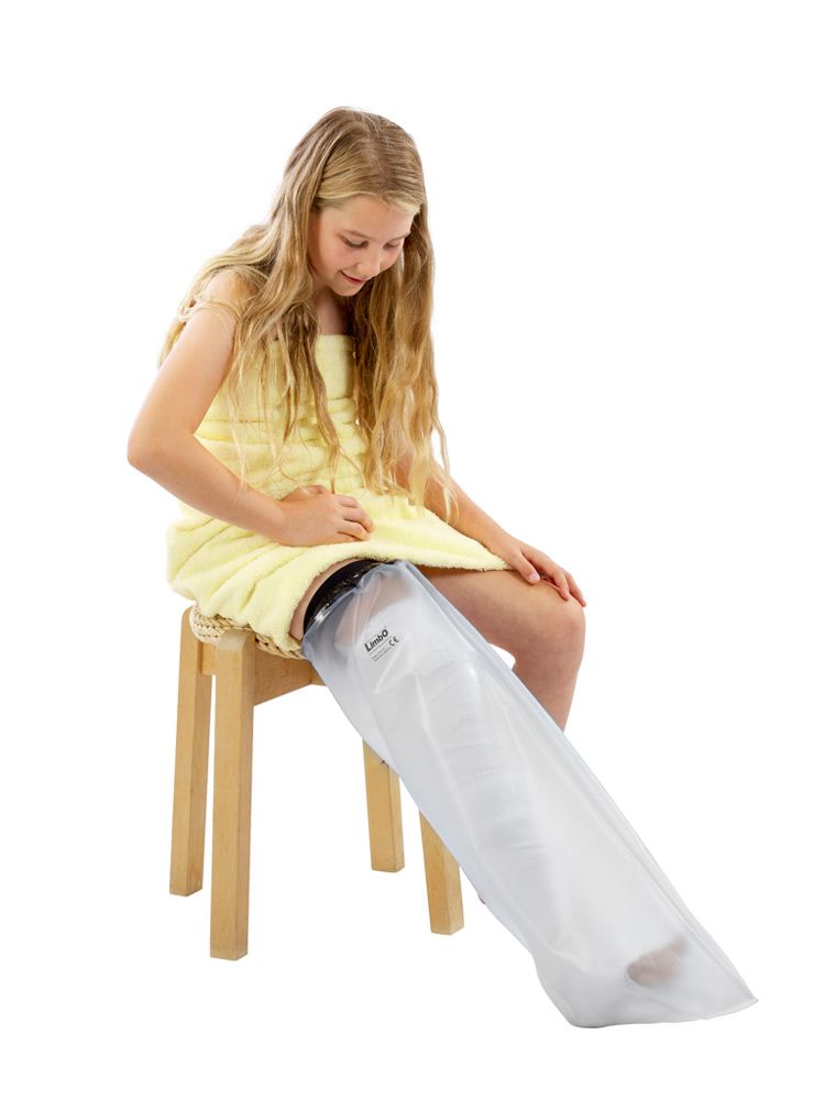 Fille avec jambe protégée. Protection étanche, embout noir, enveloppe transparente. Assise sur un tabouret, serviette jaune.