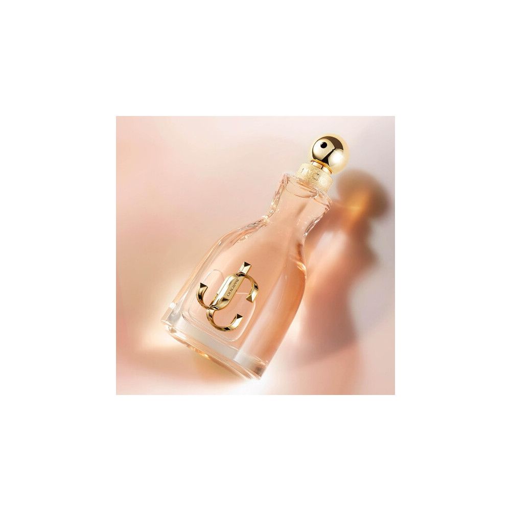Flacon de parfum en forme de robe avec logo JC doré et bouchon.