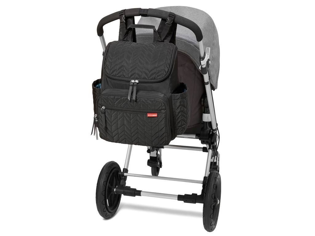 Zwarte luiertas bevestigd aan een kinderwagen. Zigzagpatroon, meerdere vakken en ritsen. Rode merknaam.