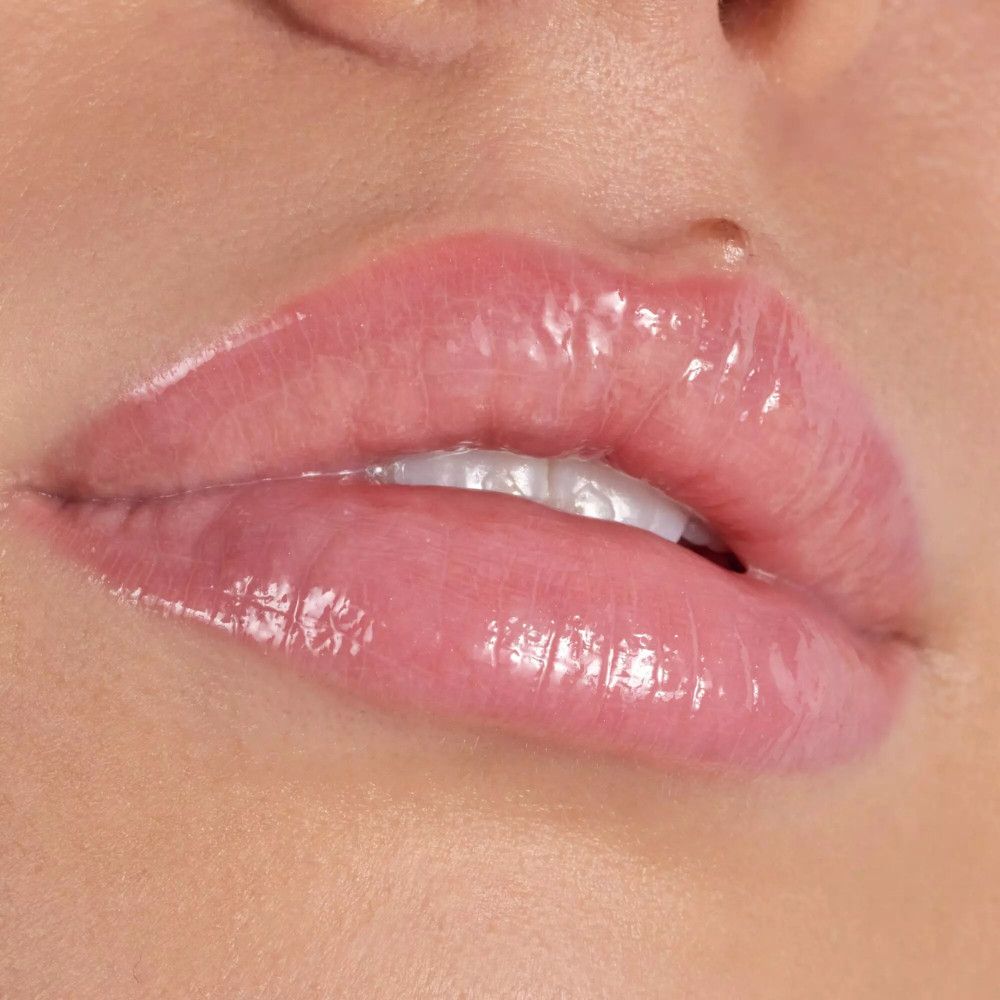 Close-up van lippen met glanzende, roze lipgloss. De lippen zijn licht geopend.