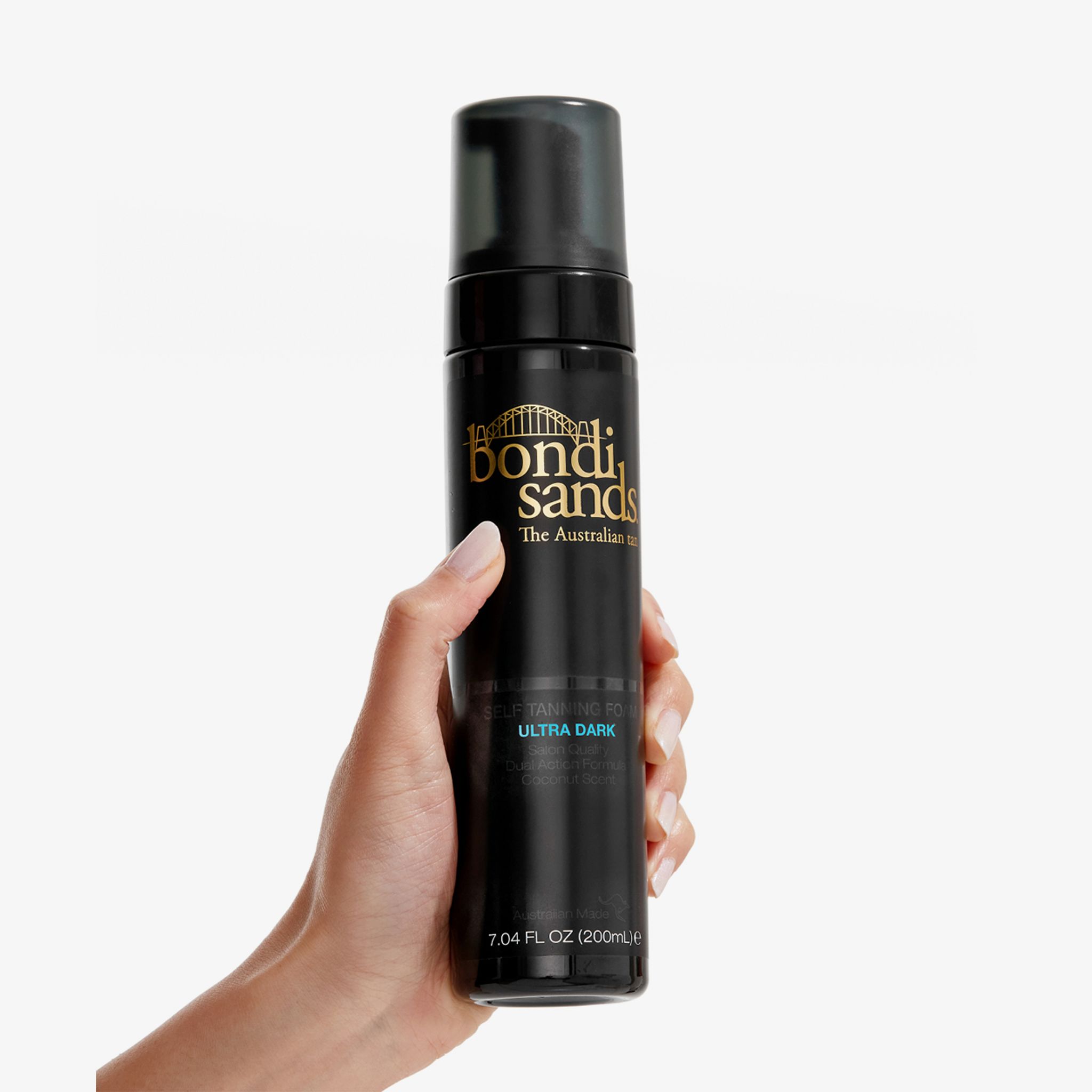 Hand houdt een zwarte fles met zwarte sproeikop. Opschrift: Bondi Sands, Ultra Dark zelfbruiningsschuim. 200ml.