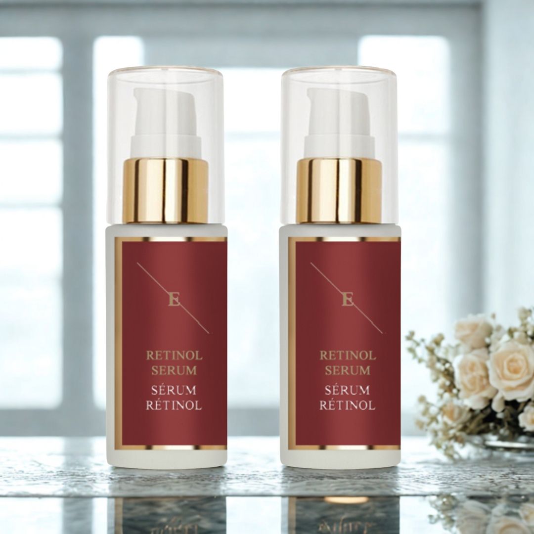 Deux flacons de sérum avec pompes. Étiquettes rouges avec texte blanc: RETINOL SERUM, RETINOL en dessous. Détails dorés. Sur table avec fleurs.