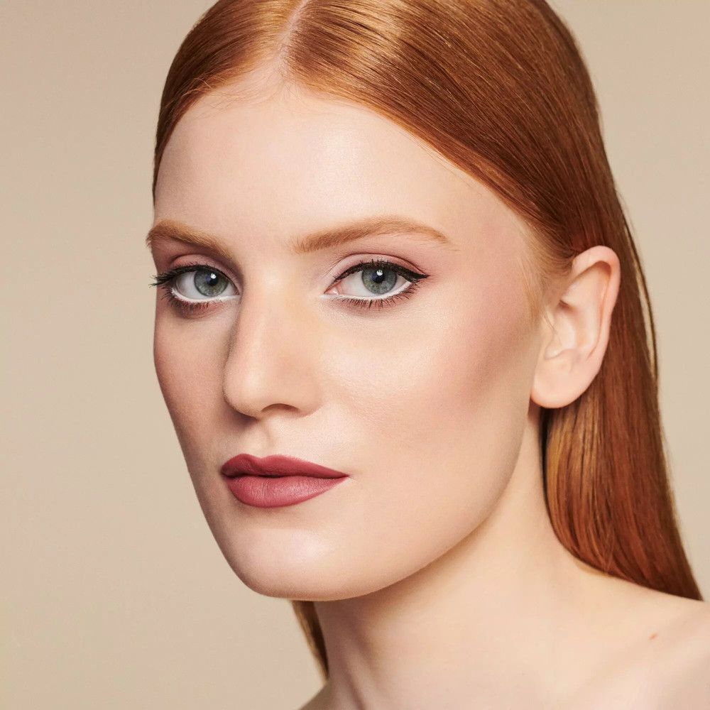 Portrait d'une femme maquillée. Accent sur les yeux et les lèvres. Rouge à lèvres rouge, maquillage des yeux discret.