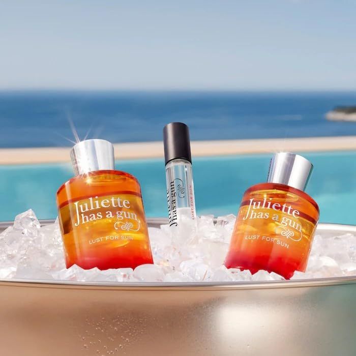 Twee parfumflessen en een kleine fles op ijs. Flessen met rood-gele kleuroverloop.