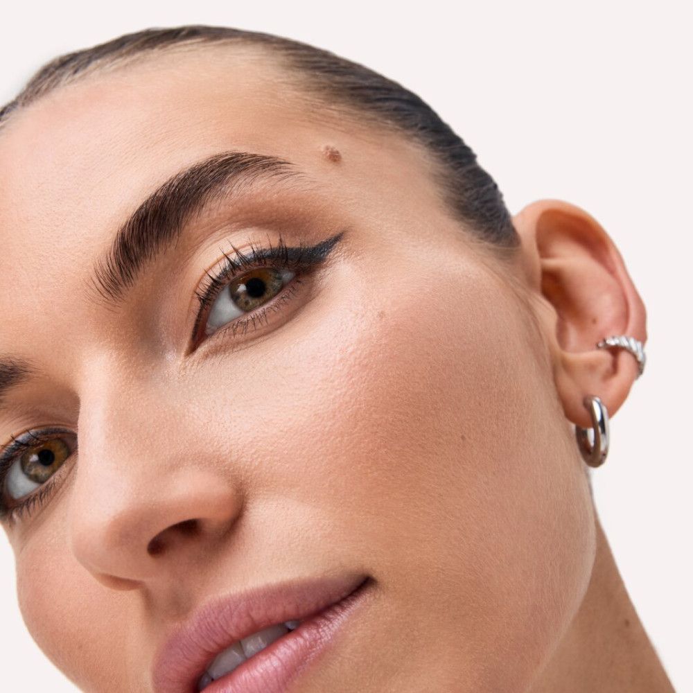Gros plan d'un visage avec trait d'eye-liner. Teint clair. Boucles d'oreilles.