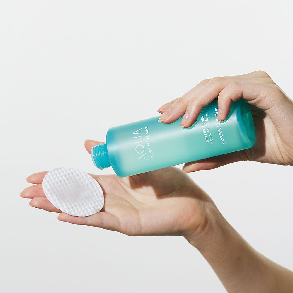 Mains tenant une bouteille turquoise et un coton. "AQUA" est visible sur la bouteille.