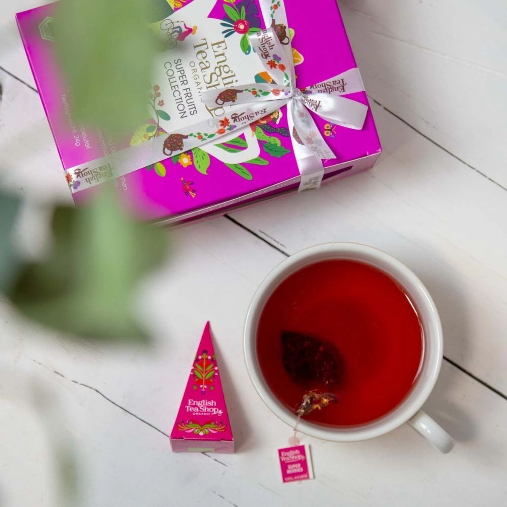 Kopje thee met piramide theezakje en theezakje label. Roze piramide theezakje ernaast. Opschrift: English Tea Shop.