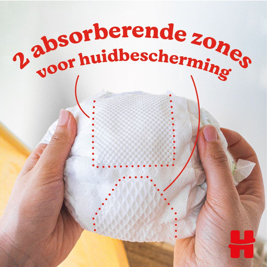 Mains tenant une couche. 2 zones absorbantes pour la protection de la peau. Logo Huggies.