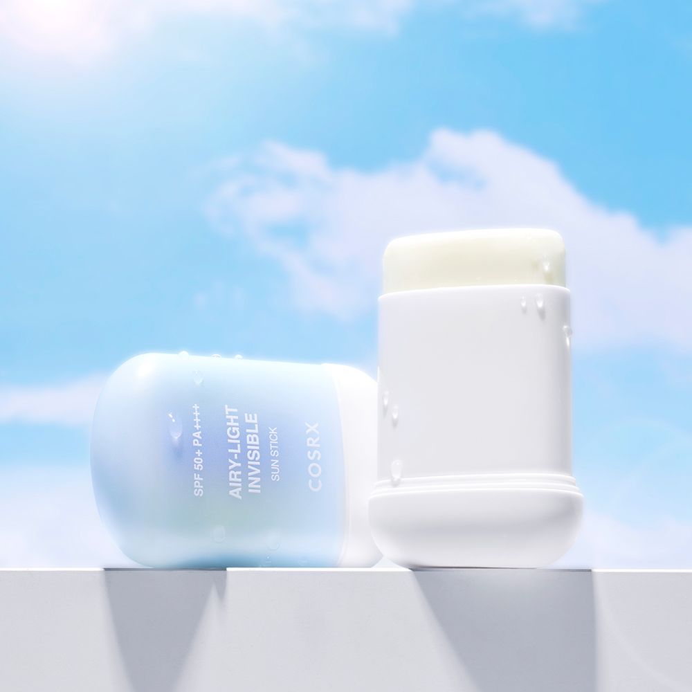 Bâton solaire COSRX sur une surface blanche devant un ciel bleu.