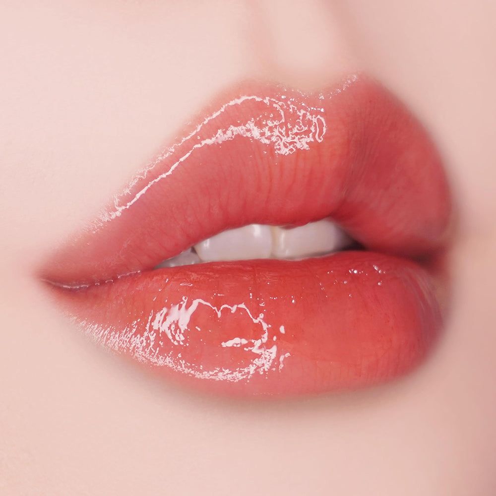 Close-up van volle, glanzende lippen. De lippen zijn rood getint en lichtjes geopend, de tanden zijn zichtbaar.