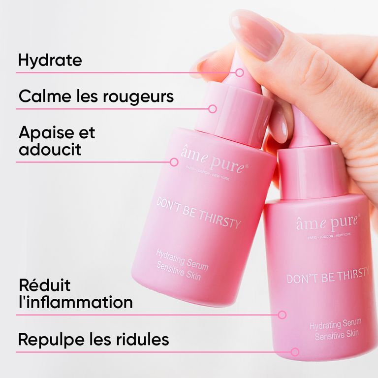 Mains tenant deux flacons roses à pipette du sérum visage "Don't Be Thirsty".