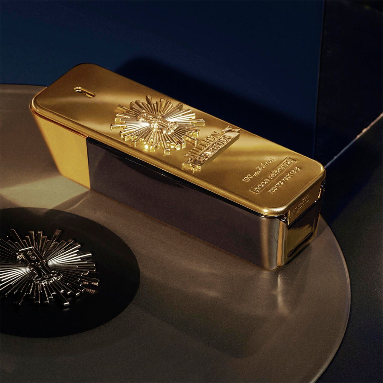 Gouden flesje, rechthoekig. Opschrift "Million Parfum". Op platen, blauwe achtergrond.