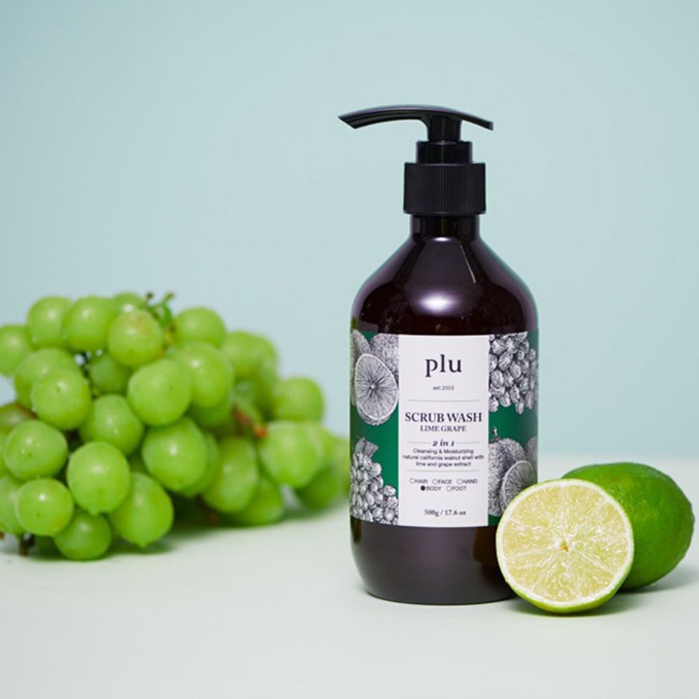 Flacon brun avec pompe noire. Inscription : PLU Scrub Wash Lime Grape. Raisins et citron vert à côté.