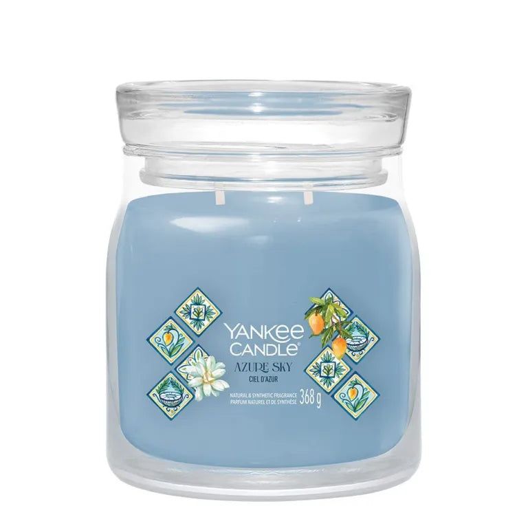 Yankee Candle Azur Sky, verre bleu, couvercle, 368g. Autocollant floral et fruits. Fond clair.