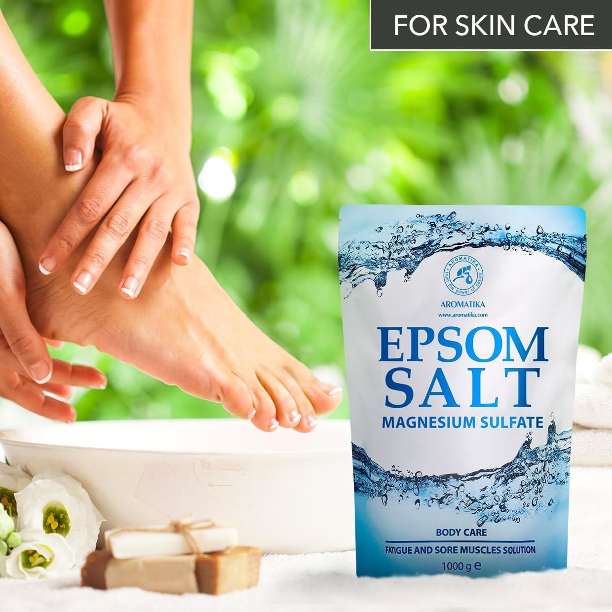 Pieds dans un bol d'eau, à côté d'un sachet de sel d'Epsom AROMATIKA et de savon.