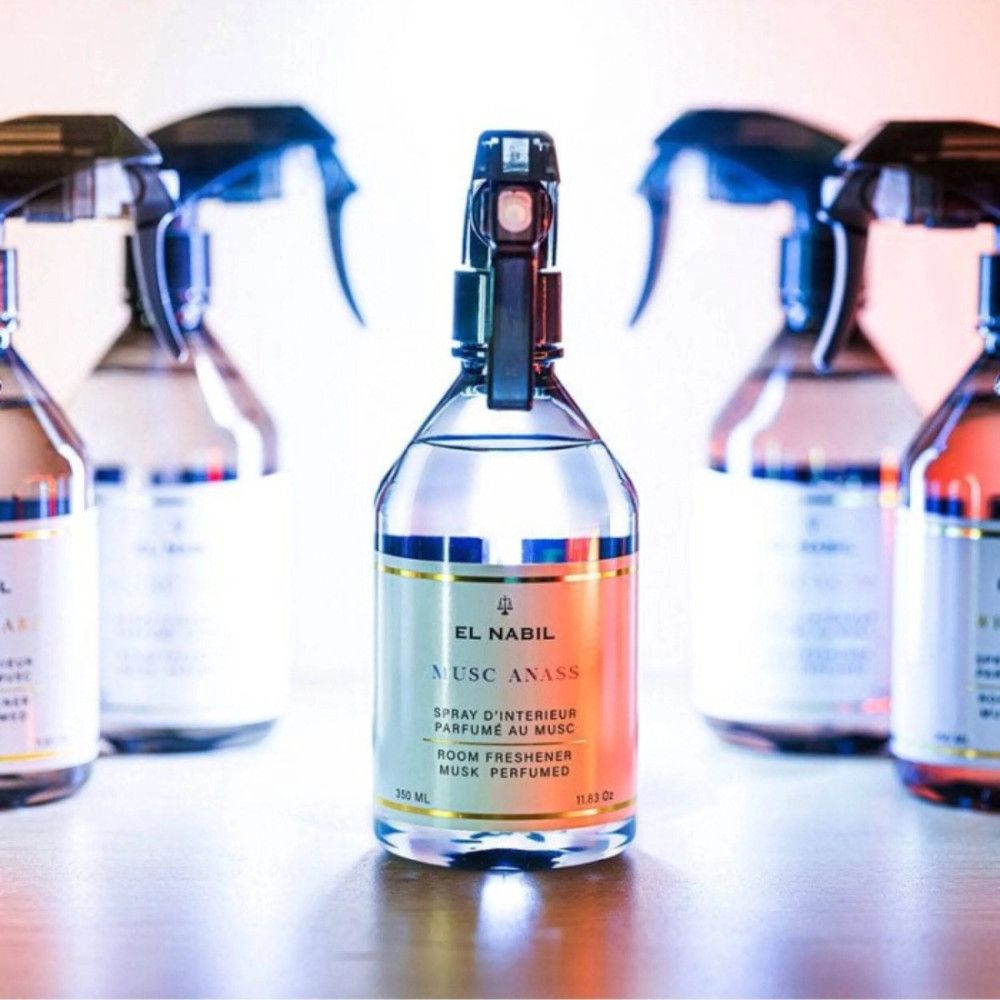 Meerdere spuitflessen met etiket. Opschrift: El Nabil, Anass Musk, geur voor de kamer. Gouden accenten.