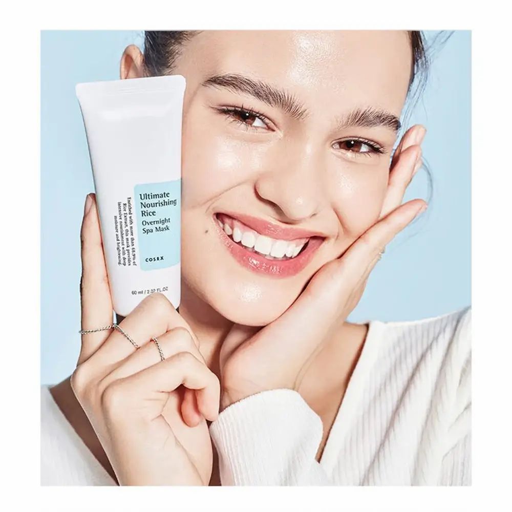 Vrouw houdt tube vast. Opschrift: Ultimate Nourishing Rice Overnight Spa Mask. Merk: COSRX. 60 ml.