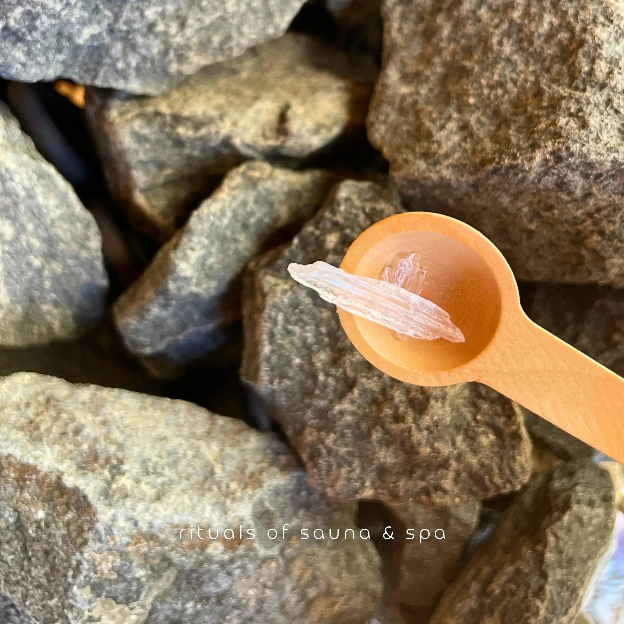 Houten lepel met mentholkristallen op stenen. Achtergrond: saunastenen.