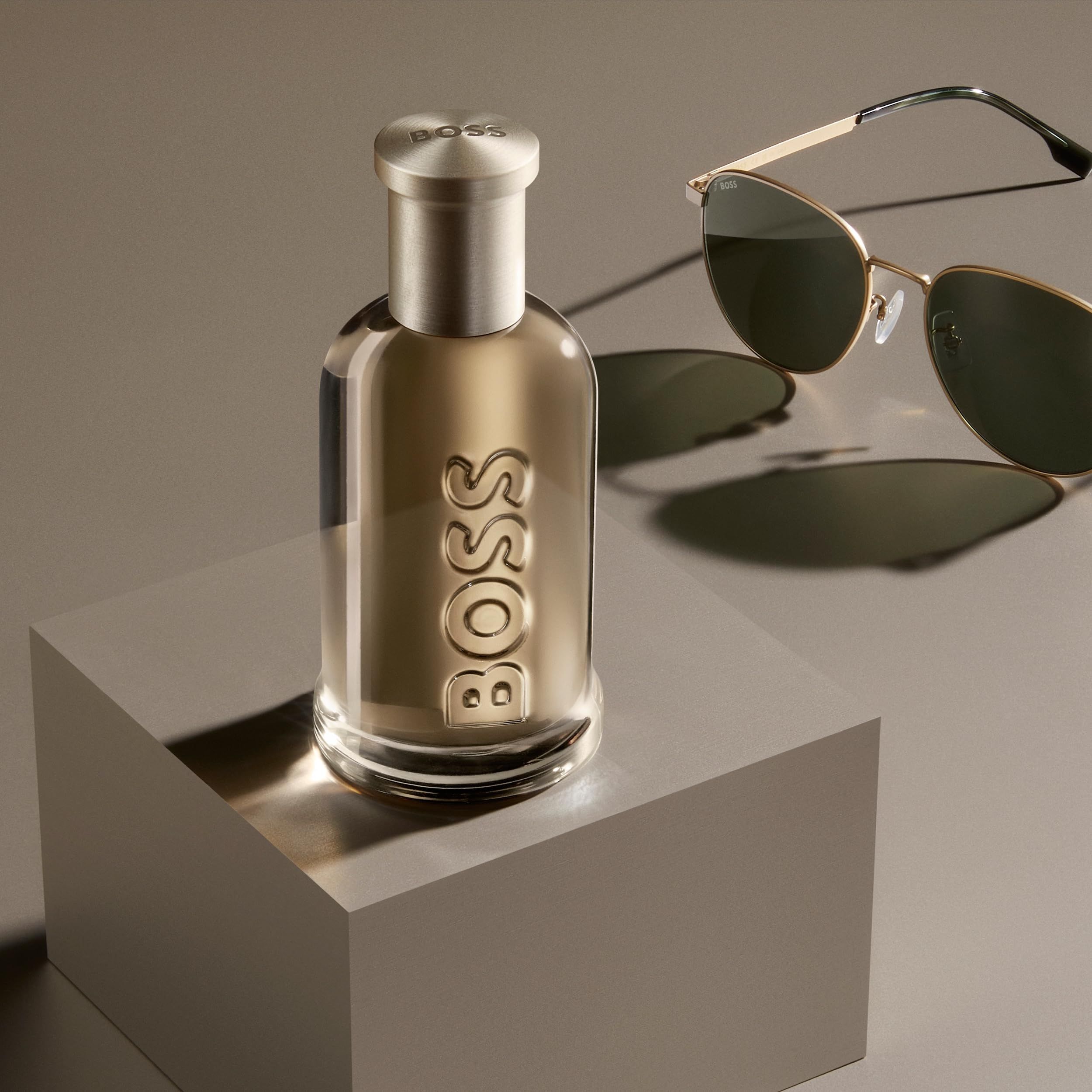 Hugo Boss Bottled Eau de Parfum fles op een kubus, naast een zonnebril.