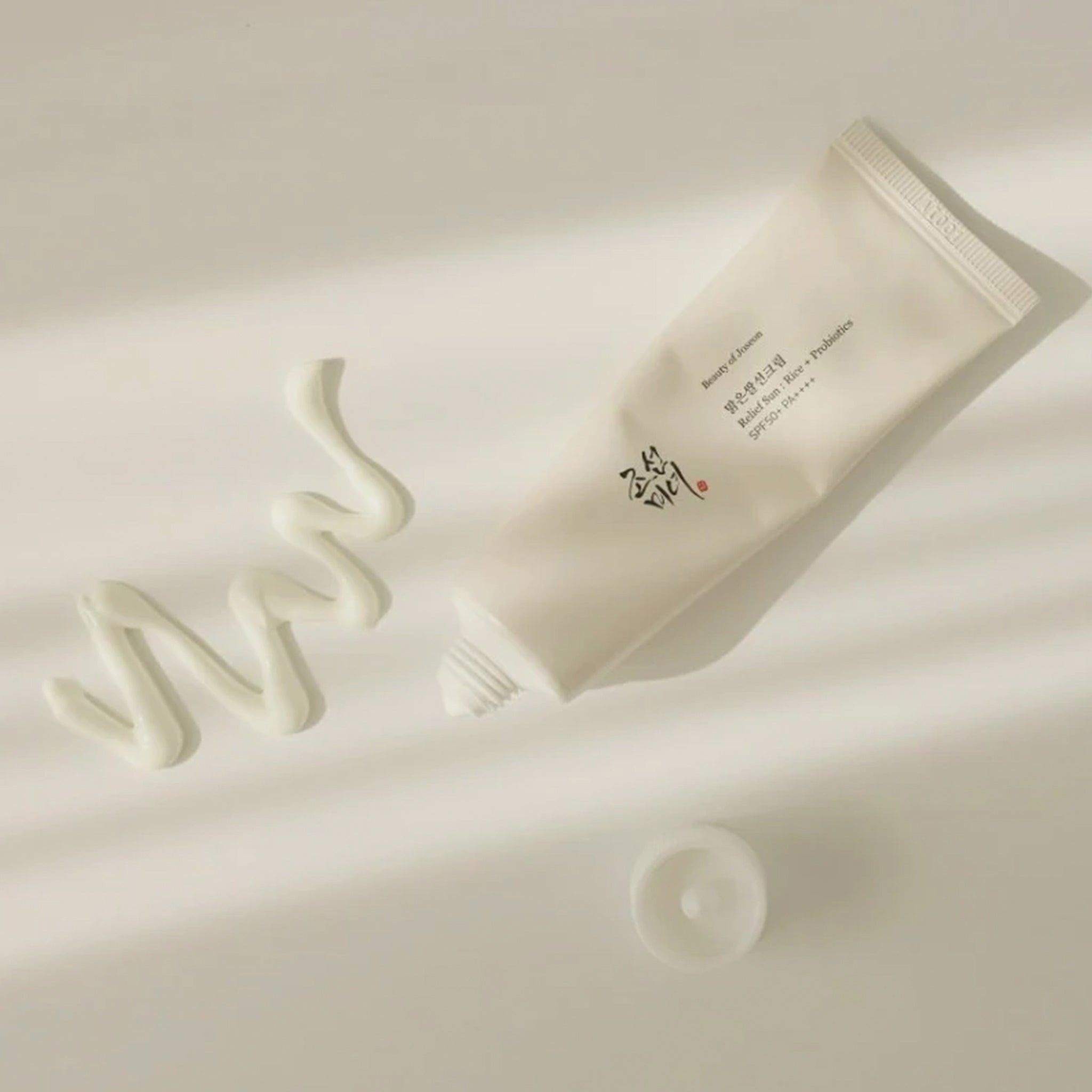 Un tube de crème et une goutte de crème à côté. Texte sur le tube.