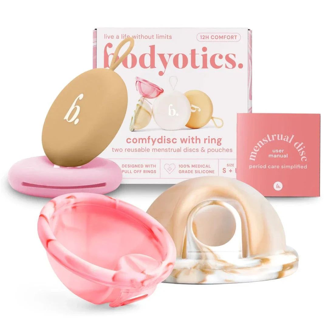 Meerdere herbruikbare menstruatiedisks en verpakking. Verschillende kleuren en vormen. Roze doos met tekst.