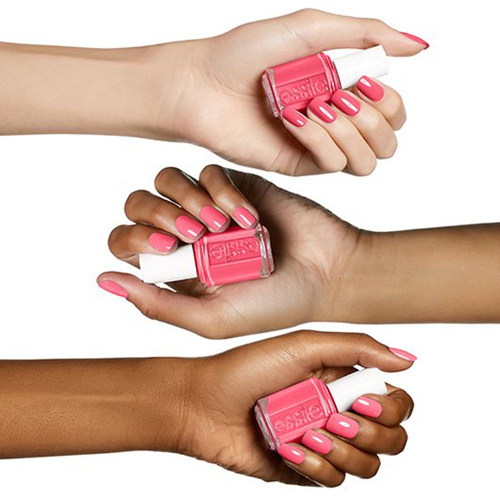 Drie handen met verschillende huidtinten houden Essie nagellakflesjes in Cute As A Button vast.