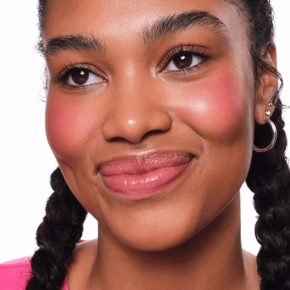 Portrait d'une jeune femme avec du blush sur les joues. Elle sourit.