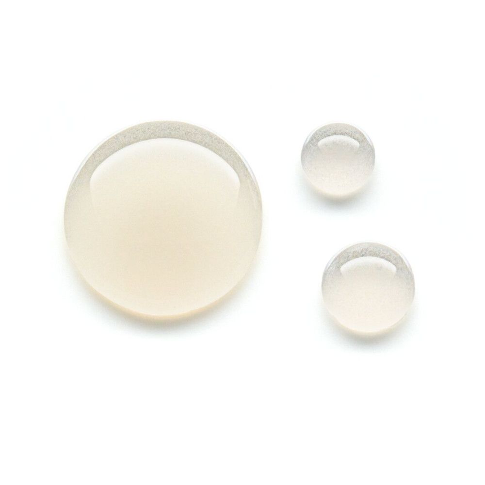 Trois gouttes de sérum sur fond blanc. Les gouttes sont claires et légèrement jaunâtres.