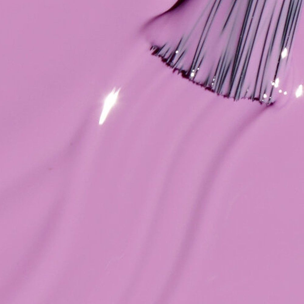 Nagellakborstel in lila vloeistof. Borstelharen wijzen omhoog. Vloeistof glanst.