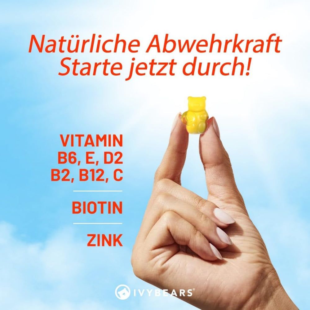 Main tenant un ourson en gélatine jaune. Texte : Vitamine B6, E, D2, B2, B12, C, Biotine, Zinc. Fond : ciel bleu.