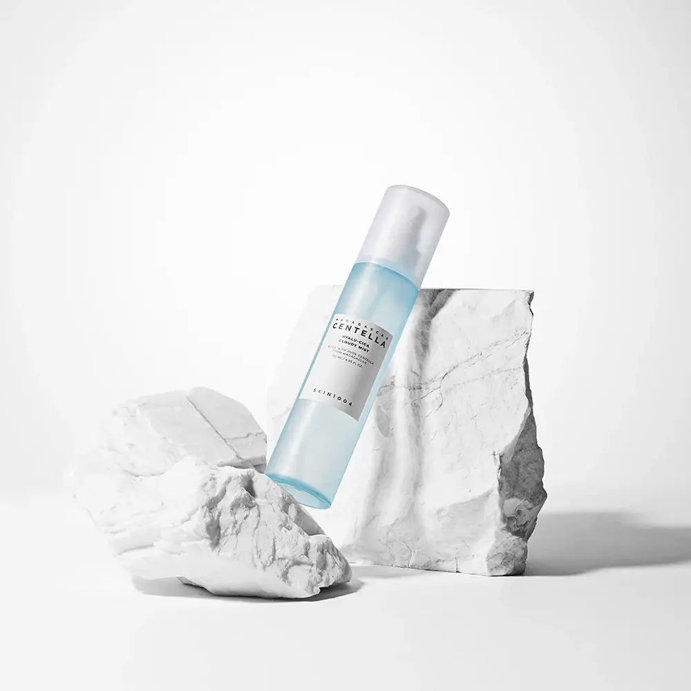 Blauwe mistfles met wit etiket. Op witte stenen, witte achtergrond.