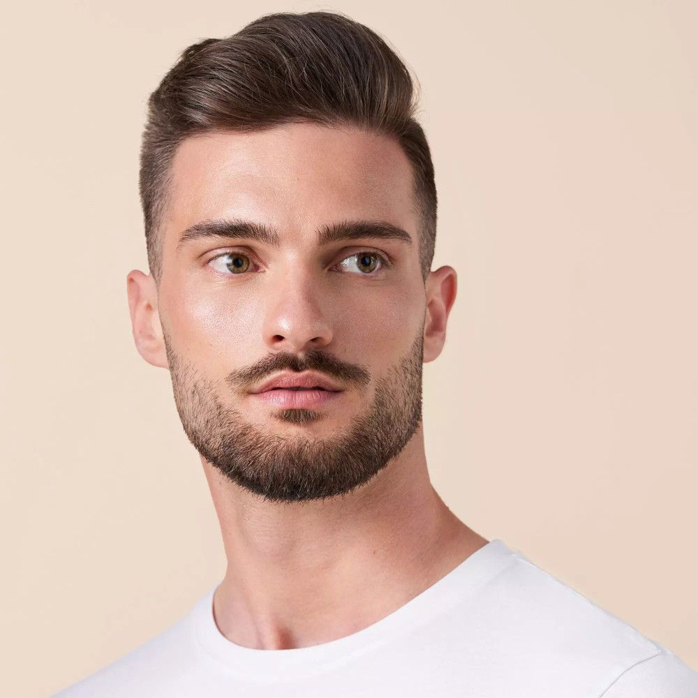 Portret van een man met baard en wit T-shirt. Hij kijkt opzij.