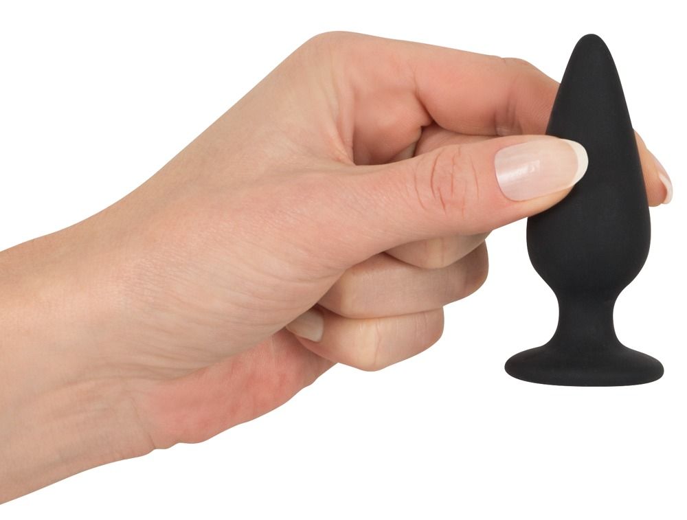 Hand die een zwarte anale plug met taps toelopende vorm vasthoudt.