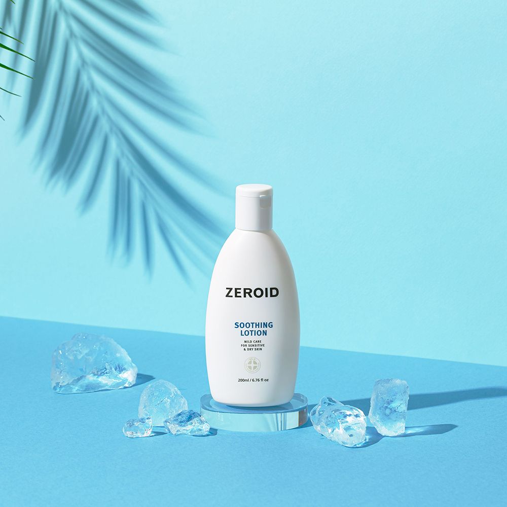 Flacon blanc ZEROID Soothing Lotion sur socle bleu, entouré de glaçons. 200ml/6.76 fl oz. Avec ombre.