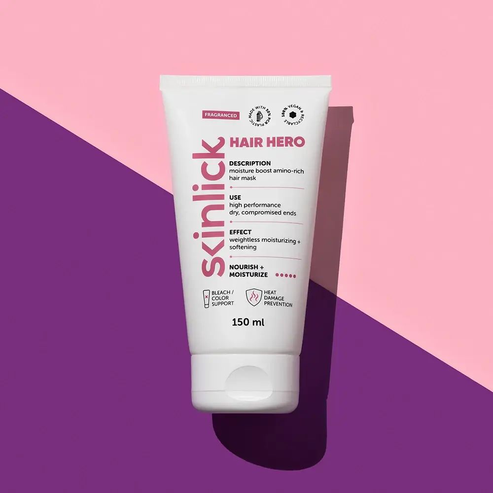 Witte tube SKINLICK HAIR HERO op roze-paarse achtergrond. Tekst: Vochtboost, aminozuurrijke haarmasker. 150 ml. Vegan, recyclebaar.