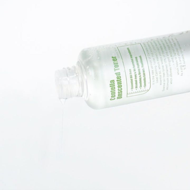 Tonerfles, vloeistof die eruit stroomt. Tekst: Centella Unscented Toner. Transparante fles, witte achtergrond.