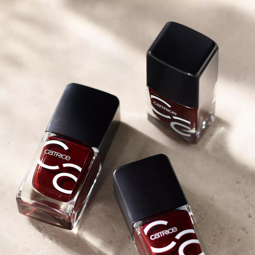 Trois flacons de vernis à ongles avec bouchon noir. Couleur bordeaux, logo Catrice sur le devant.