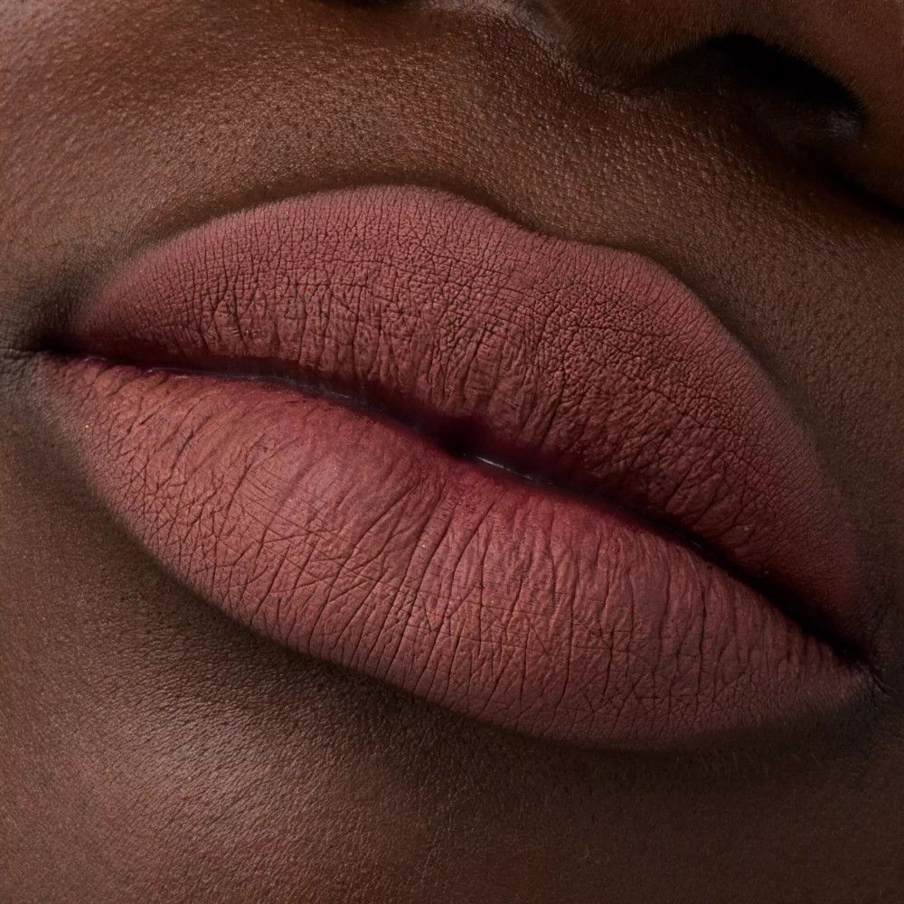 Close-up van lippen met lippenstift. De lippen zijn vol en roodbruin.