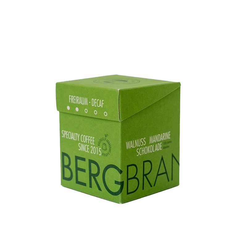 Boîte verte avec logo BERGBRAND. Texte : Freiraum-Decaf, Specialty Coffee, Walnuss Mandarine Schokolade.
