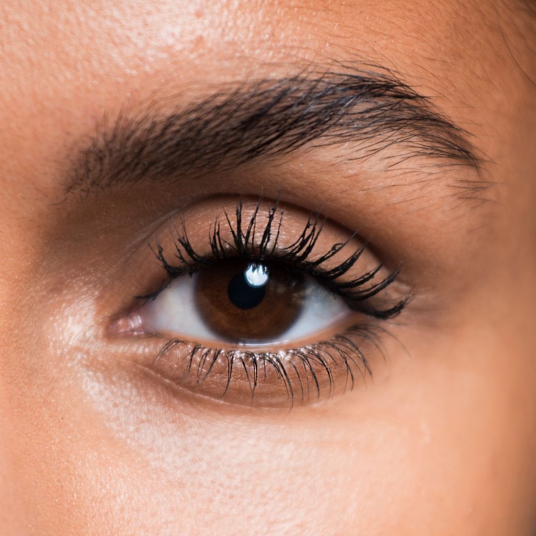 Gros plan sur un œil avec du mascara. L'œil est marron et les cils sont maquillés.