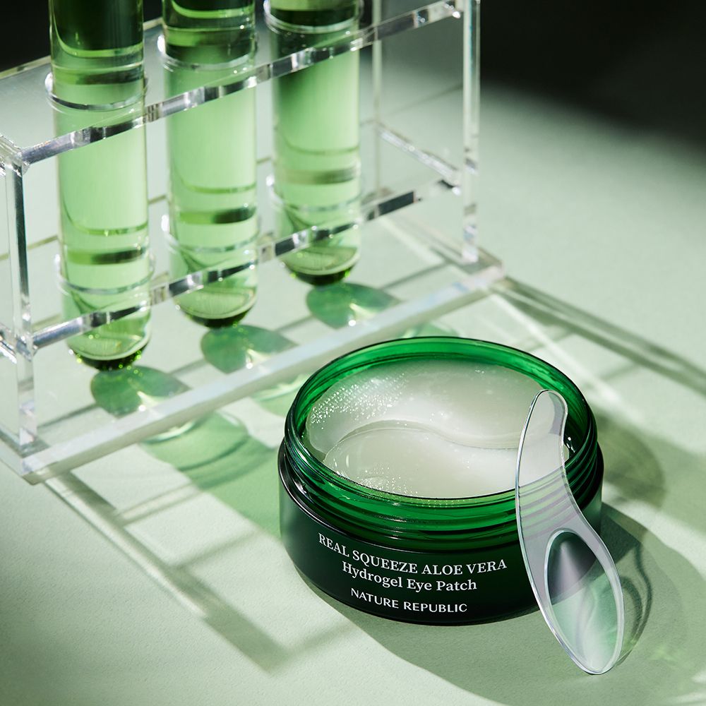 Pot ouvert avec patchs pour les yeux et applicateur. Équipement de laboratoire en arrière-plan.